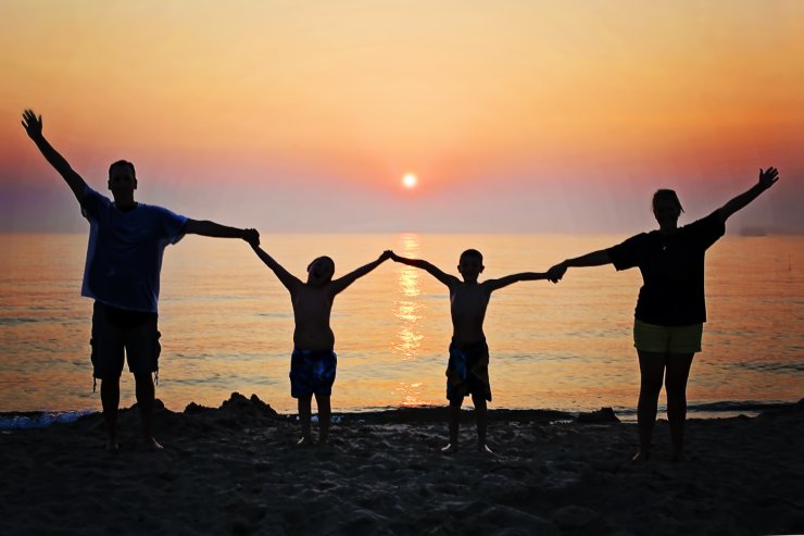 famiglia mano nella mano in riva al mare padre madre e due figli